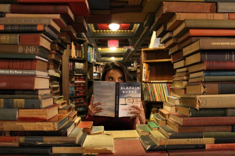 books organised into a circle with person in middle