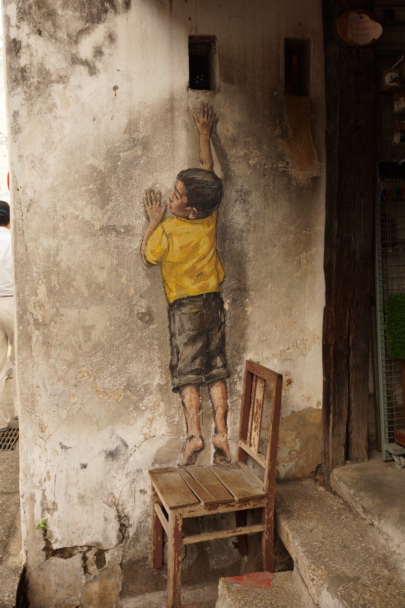 drawing of a child on a wall reaching for a real life object